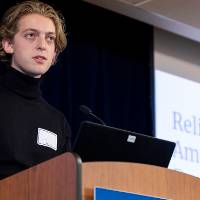 Scholar giving a presentation standing at the podium.